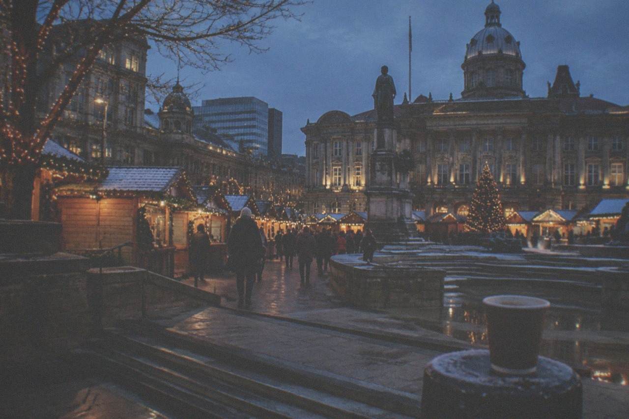 Wooden Christmas market stalls with festive lights in central Birmingham at dusk
