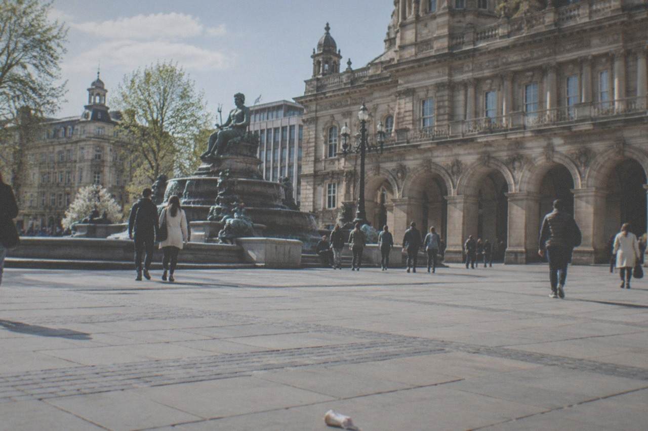 Visitors walking through Victoria Square in central Birmingham past the Council House and its fountain