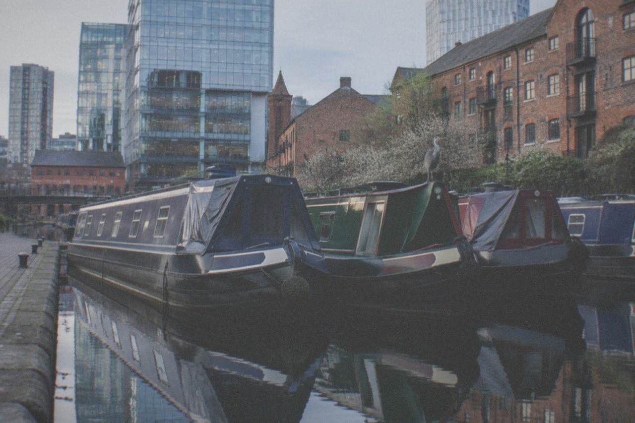 Canal boats moored at Gas Street Basin in Birmingham with city buildings behind
